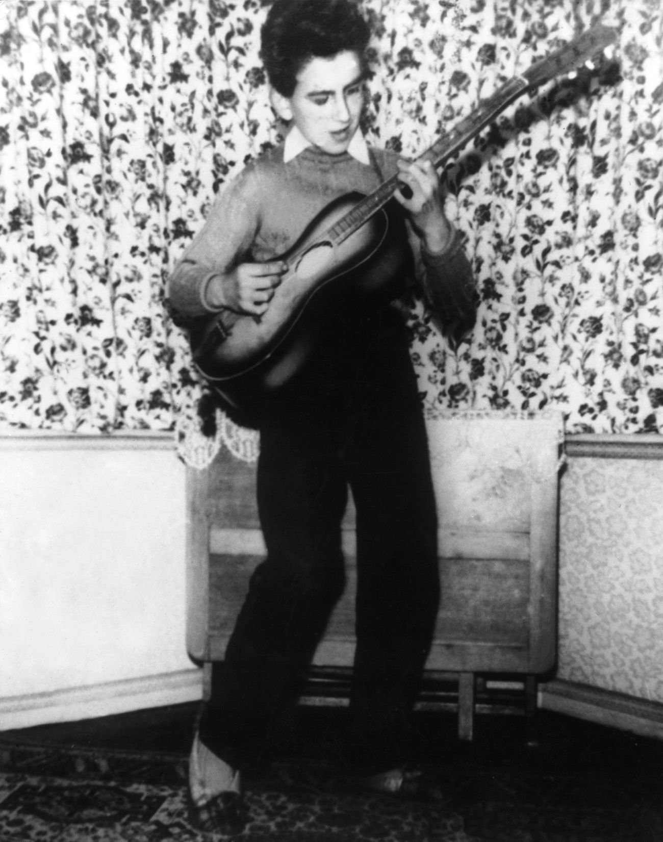 George Harrison practicing guitar in a white shirt at age 12, 1955.