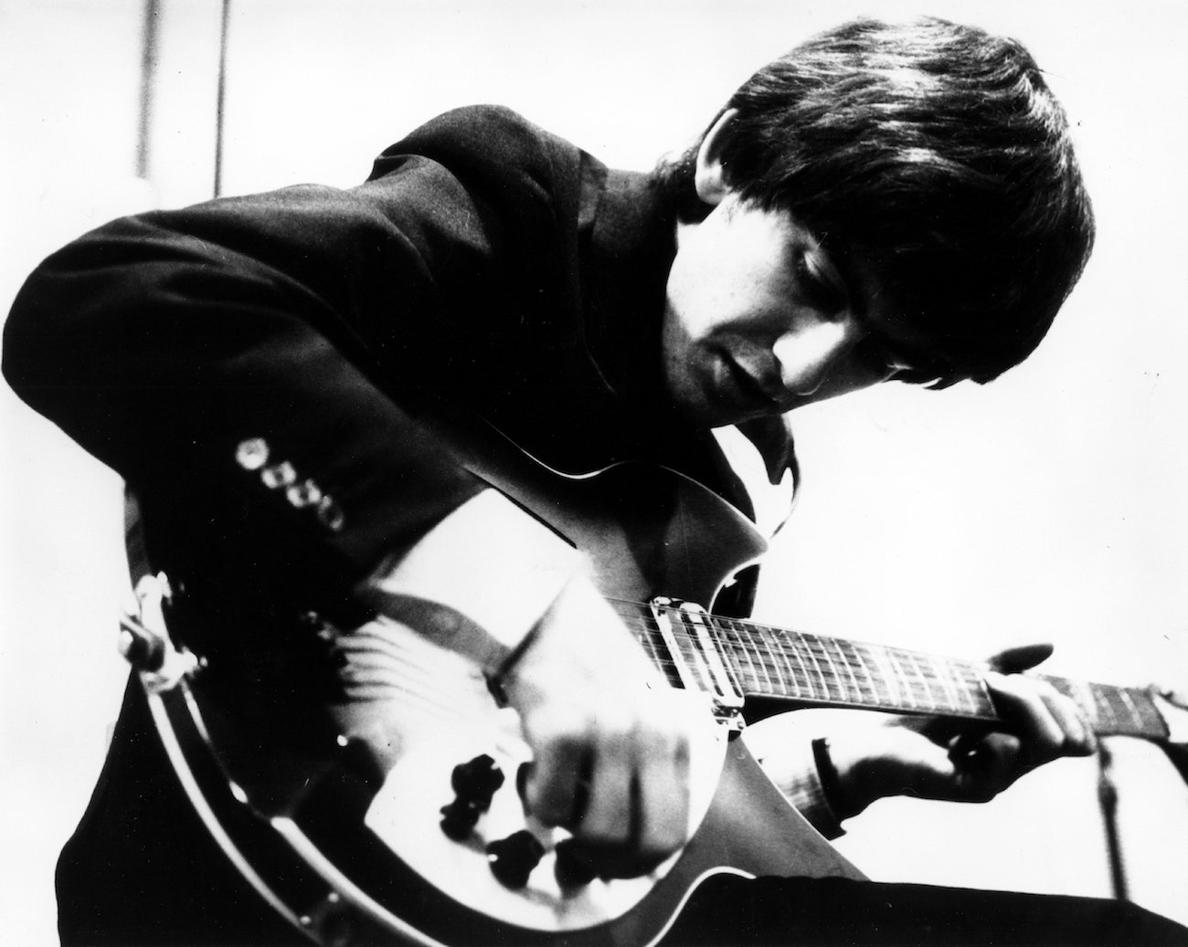 George Harrison practicing his guitar wearing black in 1964.