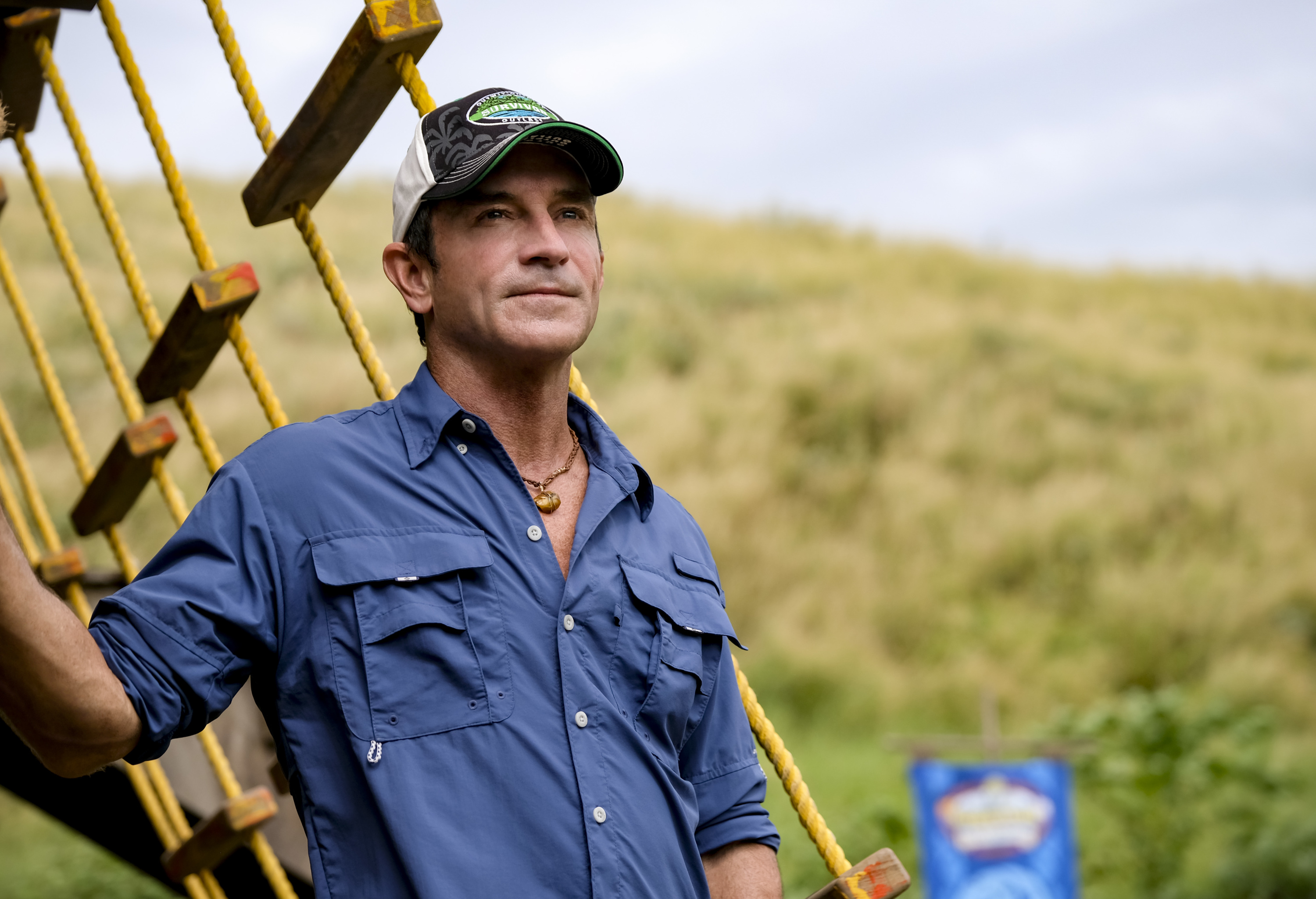 'Survivor' Season 41 host Jeff Probst wears a blue button-up shirt and a 'Survivor' hat.
