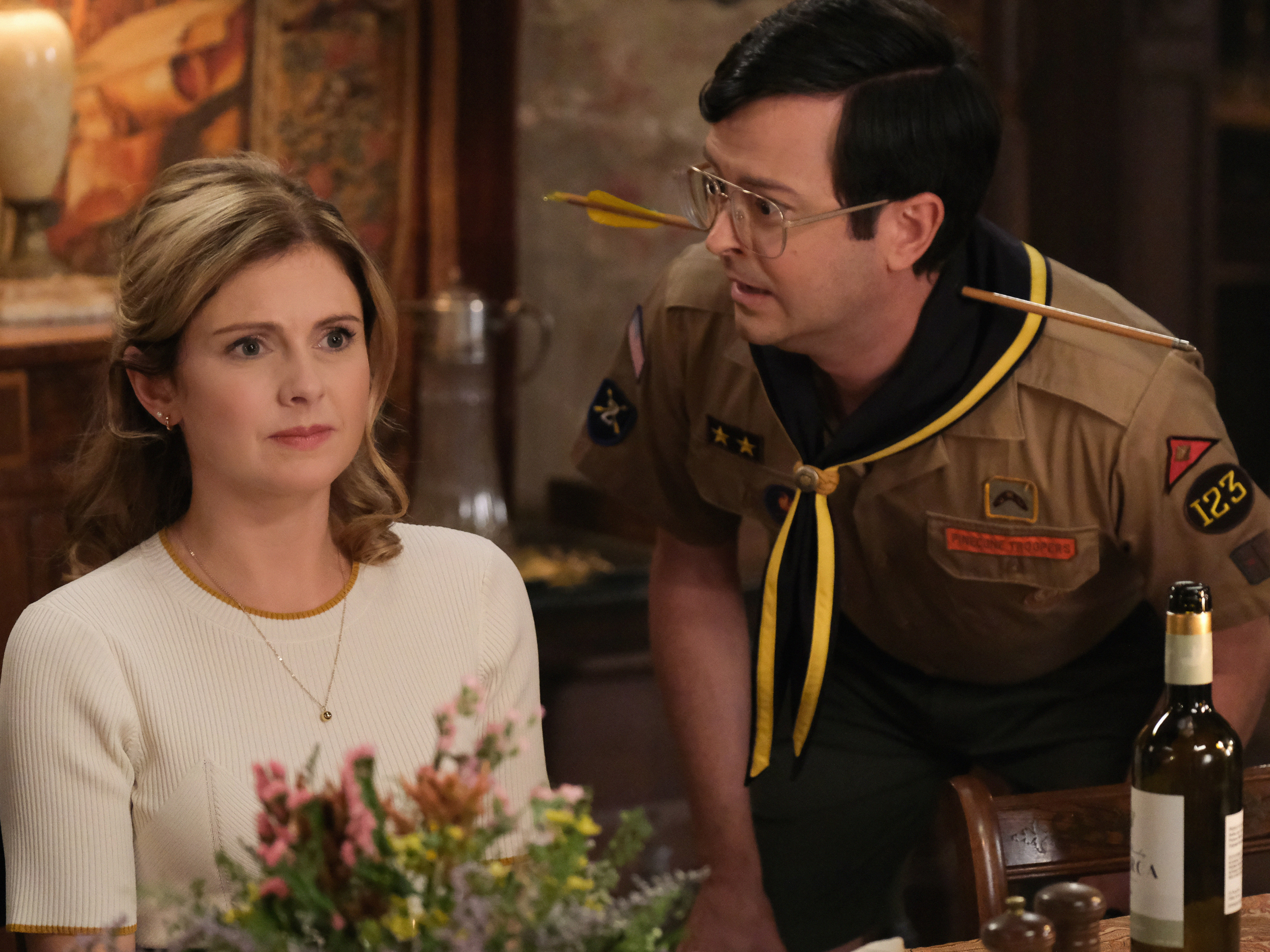 'Ghosts' actor Rose McIver in a white blouse, and Richie Moriarty in a Boy Scout uniform in a scene from the series.