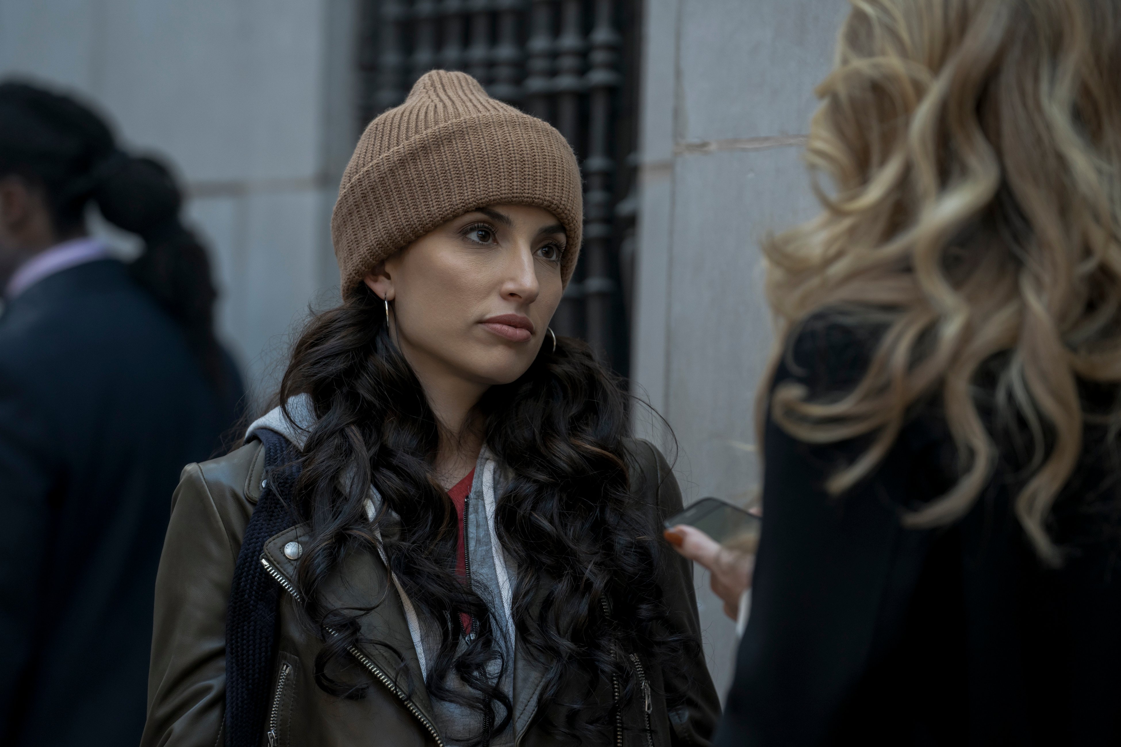 Tania Raymonde as Brittany, wearing a knit hat and looking at a blonde woman, in 'Goliath' Season 4