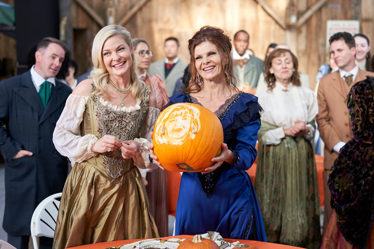 Two women in Halloween costumes holds a carved pumpkin in 'Good Witch Curse From a Rose'