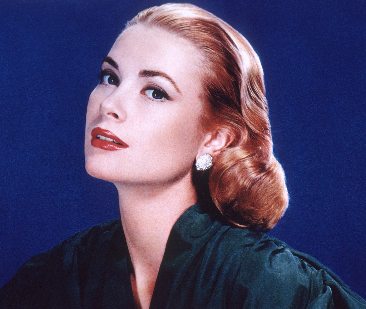 Grace Kelly smiling in front of a blue background