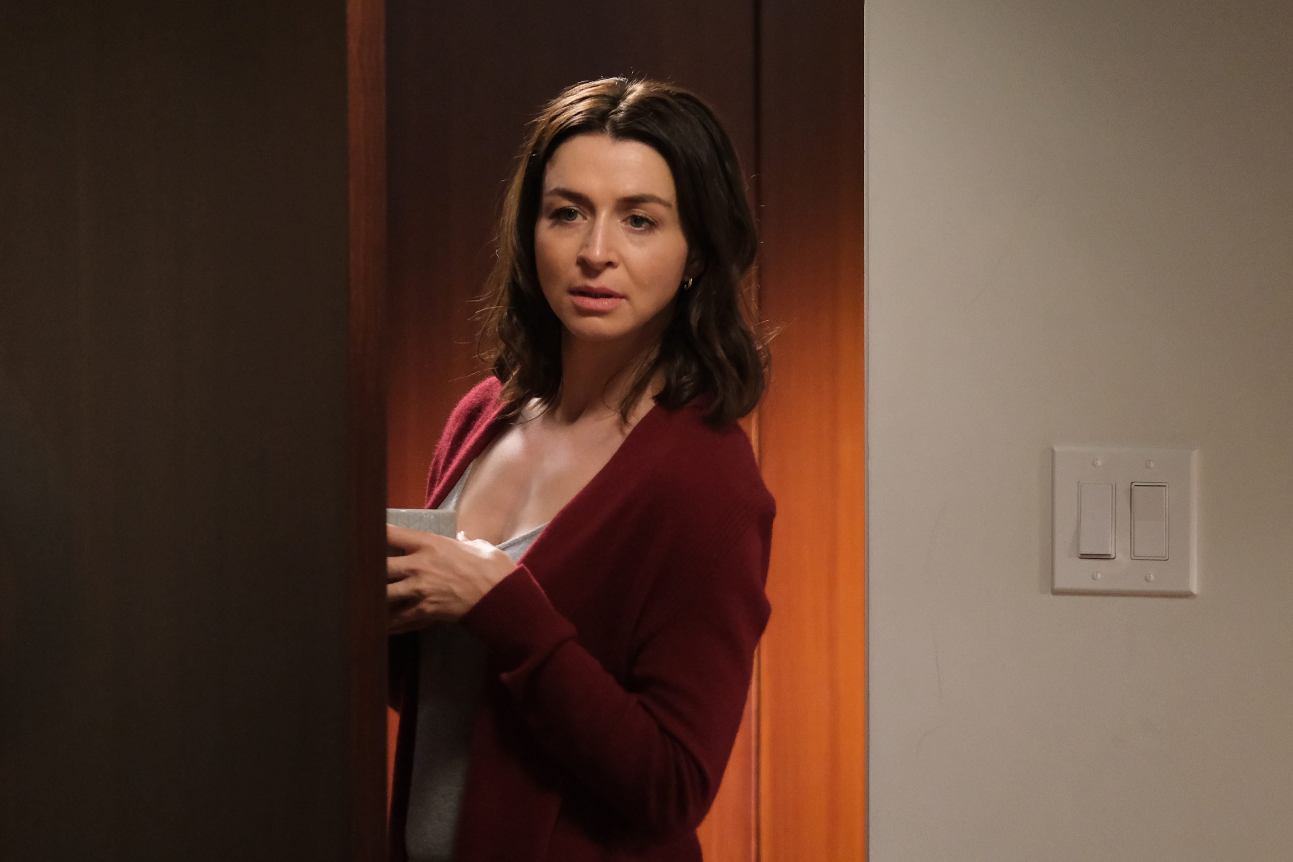 Caterina Scorsone as Amelia Shepherd on 'Grey's Anatomy' stands by an open door.