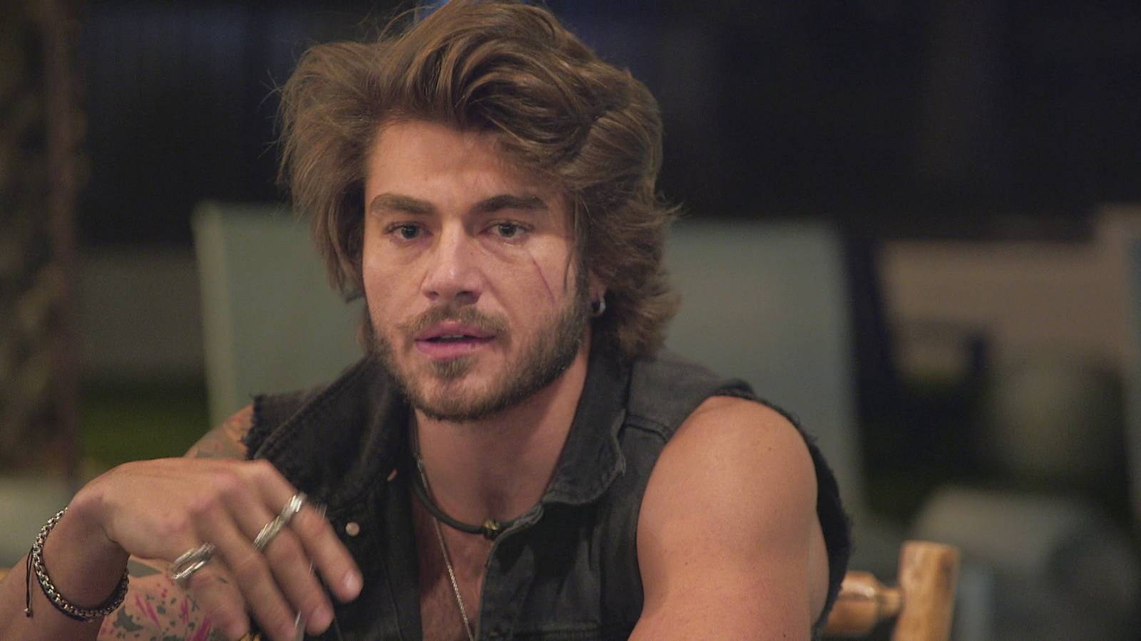 'Floribama Shore' star Gus Smyrnios sits at the table with his hand slightly raised