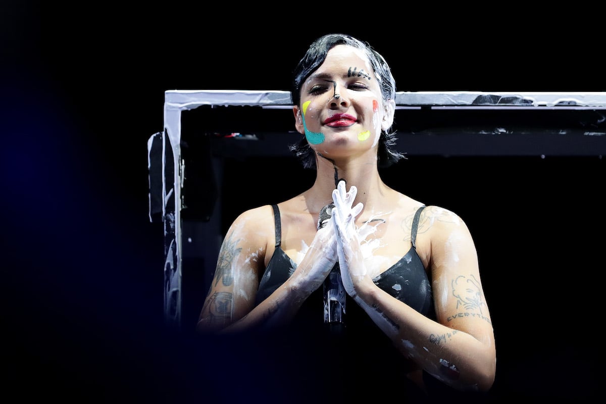 Halsey performs on stage while covered in paint splatters.