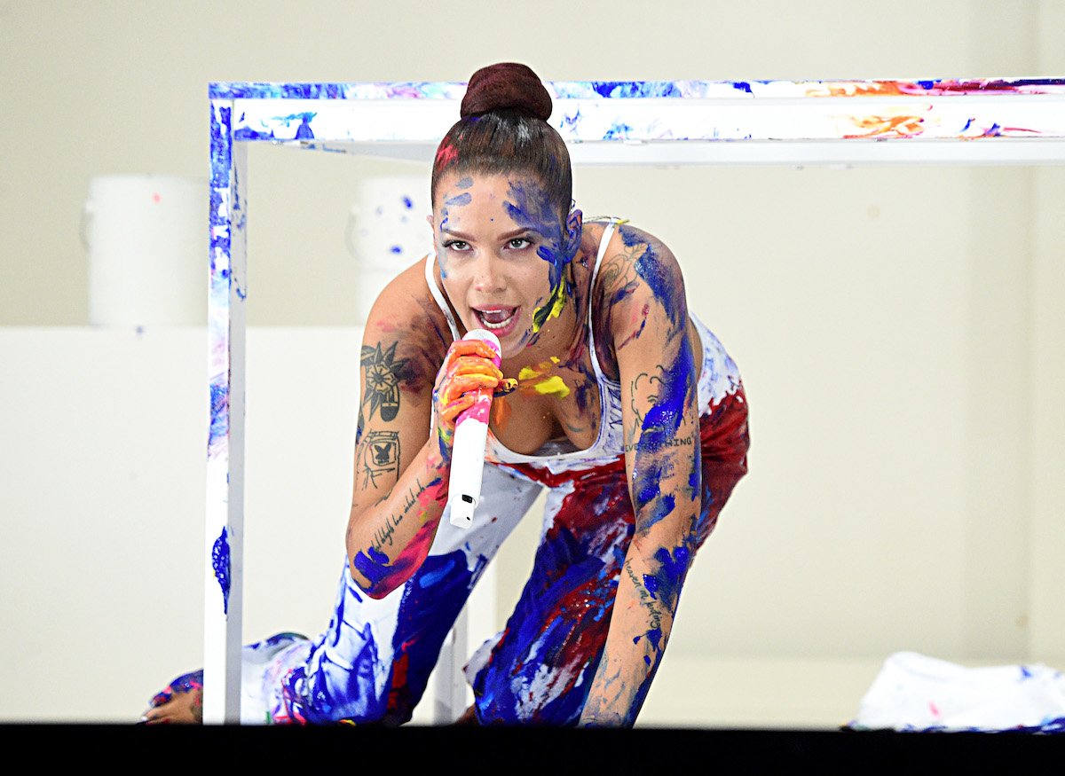 Halsey performs on stage in a white outfit covered with paint splatters.