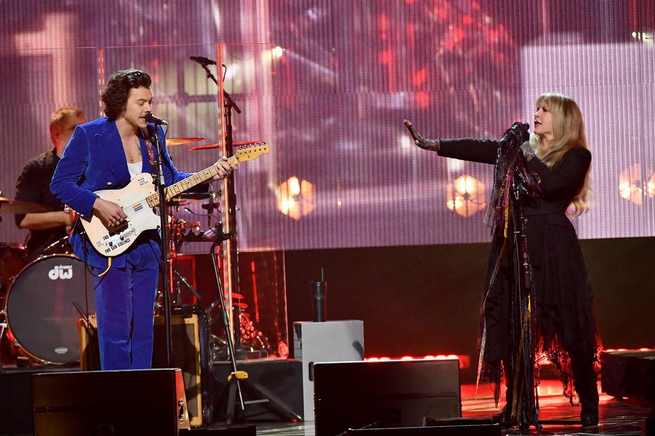 Harry Styles and Stevie Nicks perform together on stage at the Rock and Roll Hall of Fame. Styles plays guitar.