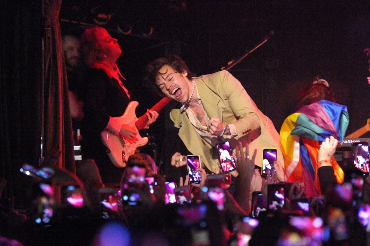 Harry Styles performs in a tan suit, on stage in front of a crowd