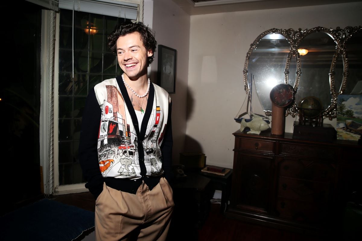 Harry Styles smiling in pearl necklace and cardigan