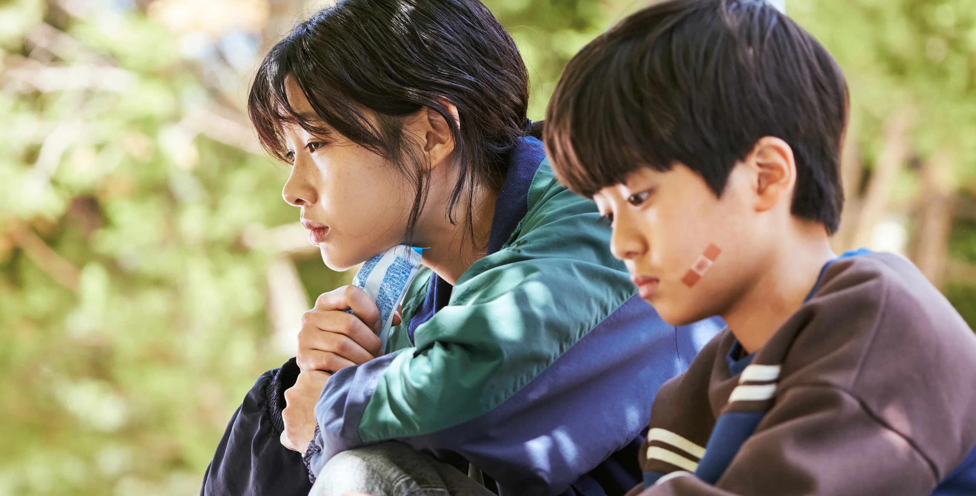 HoYeon Jung as Kang Sae-byeok for 'Squid Game' sitting next to young boy.