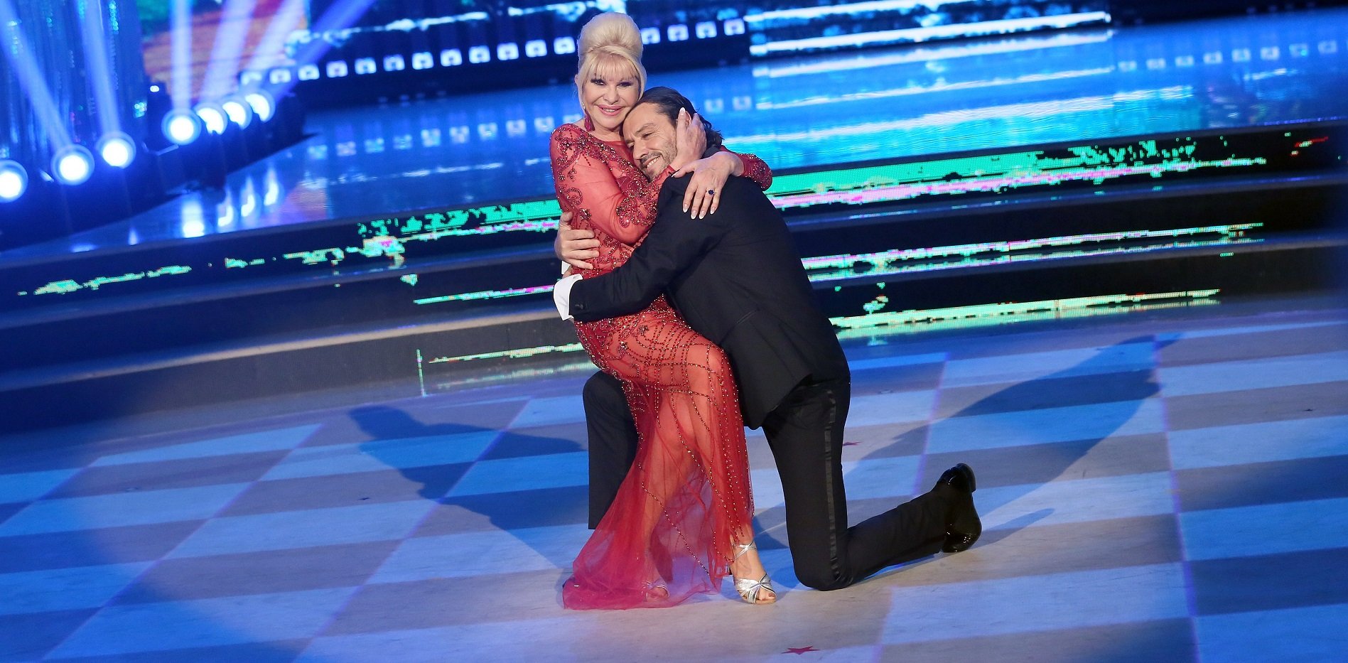 Ivana Trump in a red dress, cradling Rossano Rubicondi, who is in a black suit