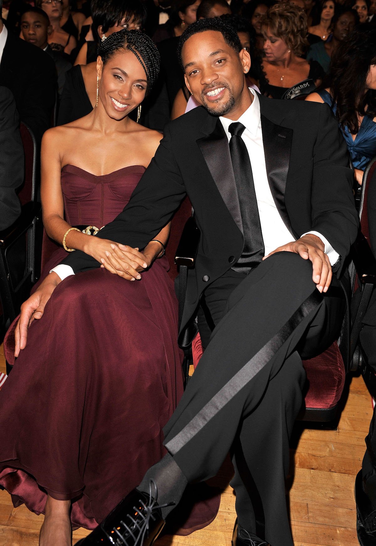 Jada Pinkett Smith and Will Smith sitting next to each other and smiling at an event.