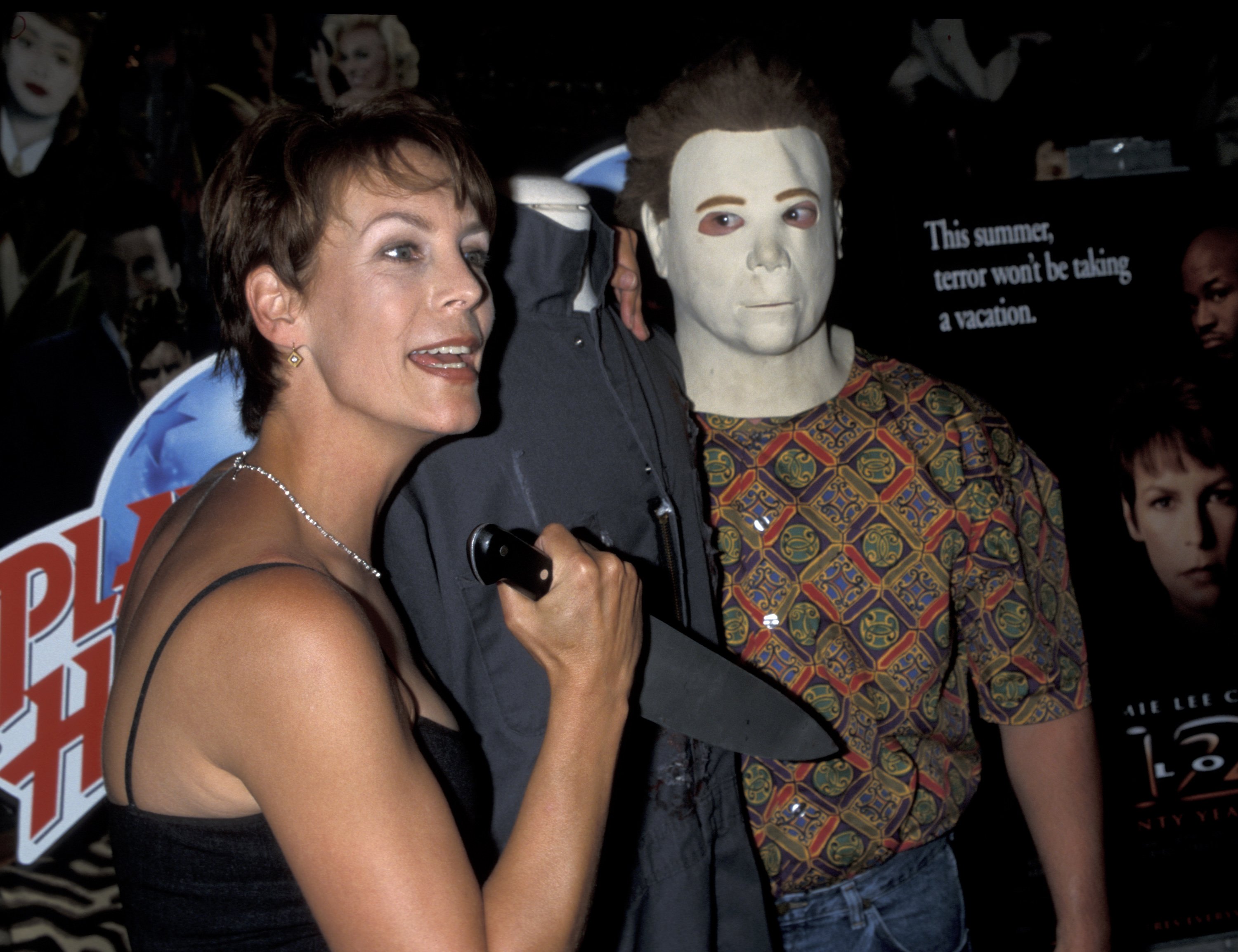 Horror movie star Jamie Lee Curtis holds a knife near a man in a Michael Myers mask. 