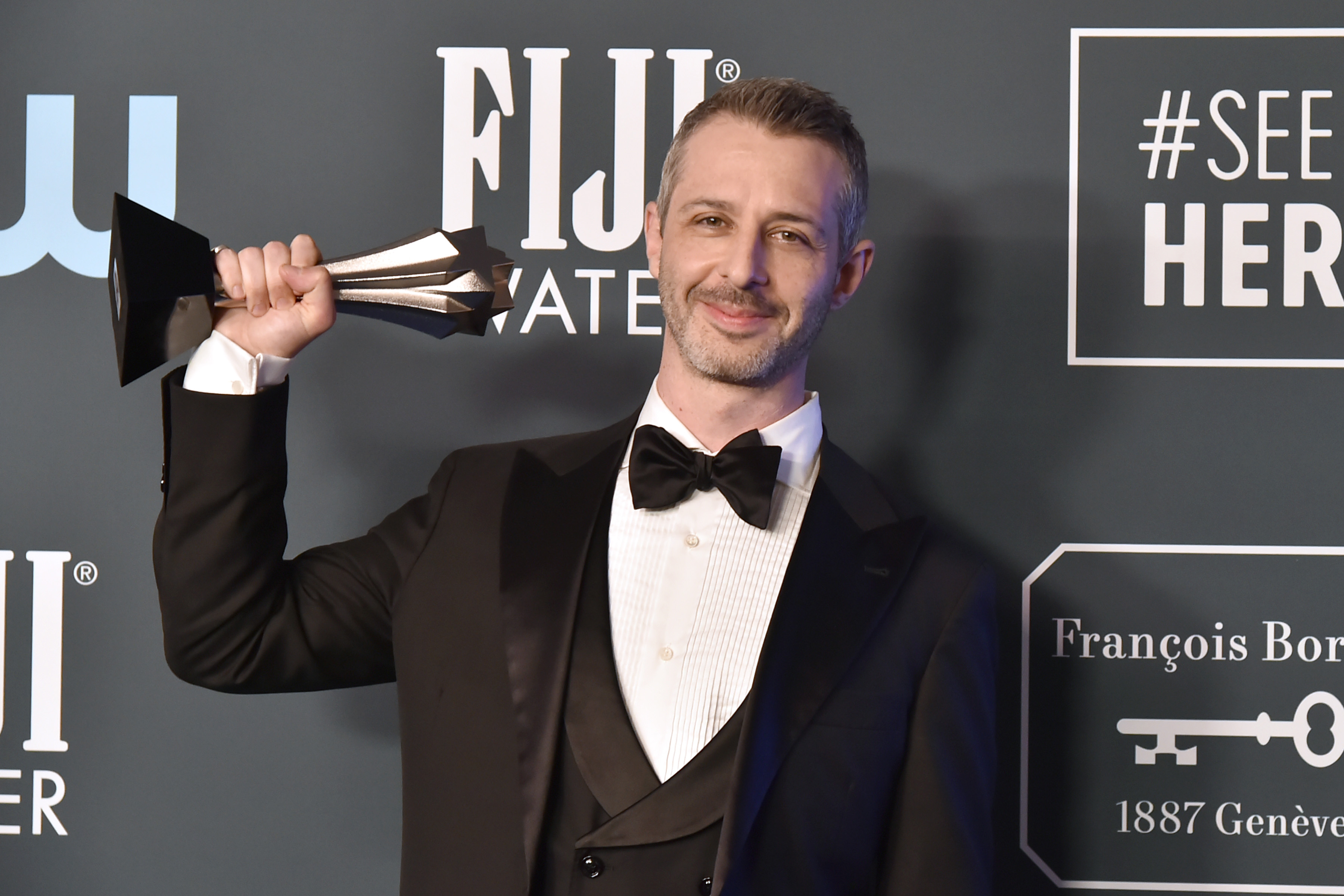 Succession Season 3 actor Jeremy Strong wears a tuxedo and holds a trophy.