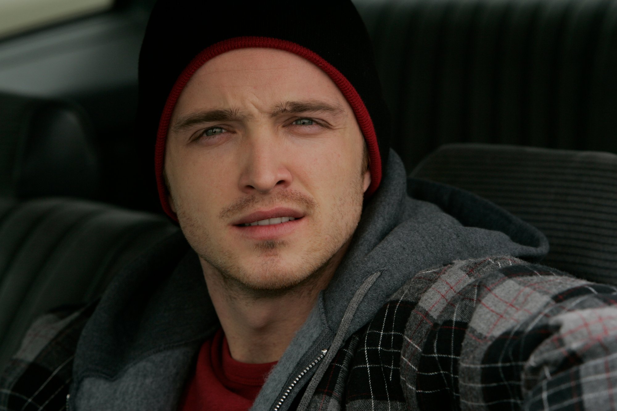 Aaron Paul as Jesse Pinkman in AMC's 'Breaking Bad.' He's sitting in a car with the window rolled down, and he's wearing a hoodie and beanie.