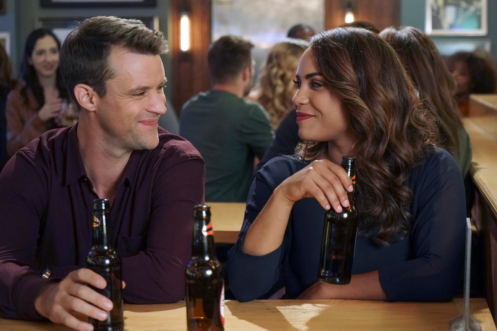 Jesse Spencer, and Monica Raymund sitting in a restaurant in 'Chicago Fire.'