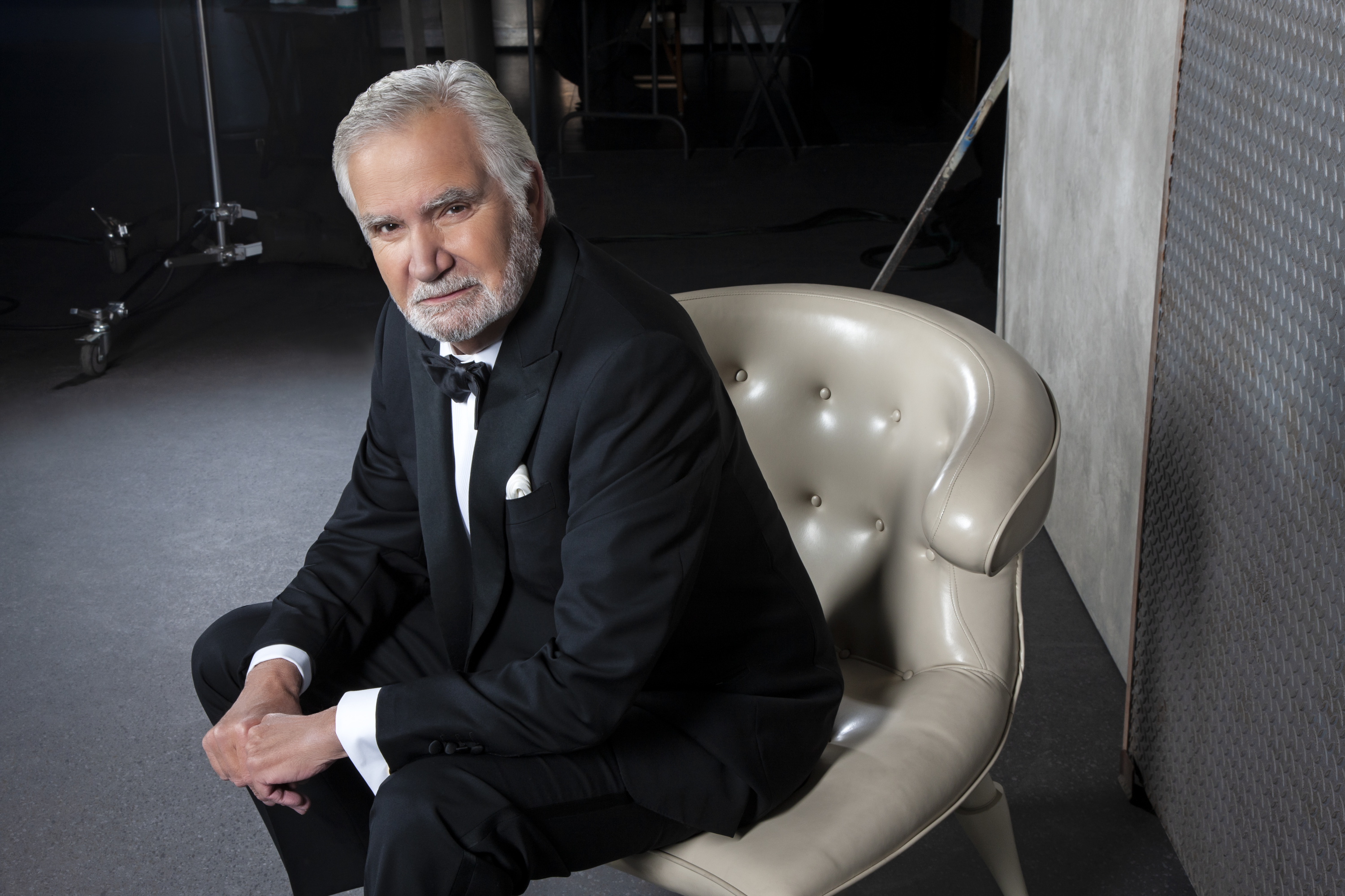 'The Bold and the Beautiful' actor John McCook wearing a tuxedo and sitting in a grey chair.