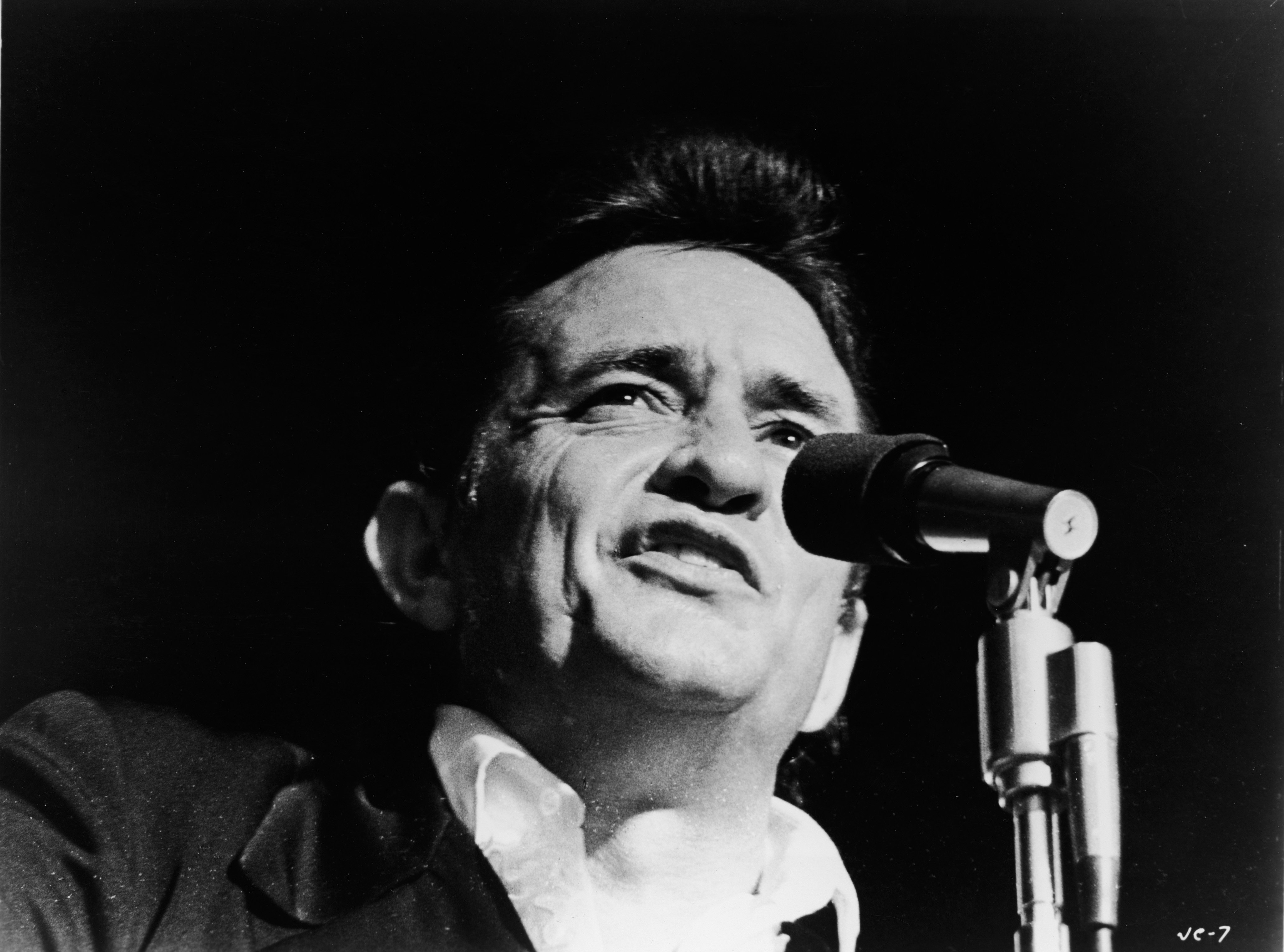 Johnny Cash sings at a microphone.