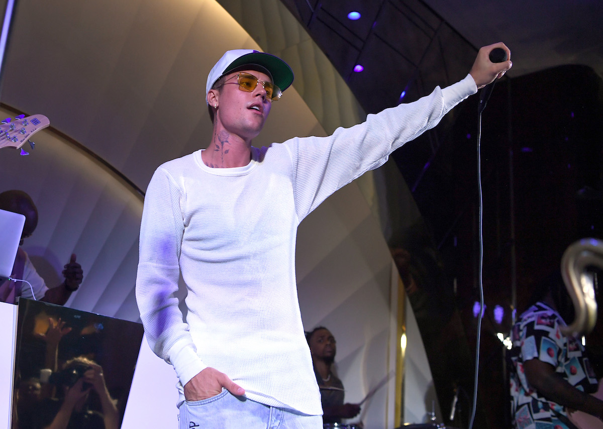 Justin Bieber holds a microphone out to the crowd from a stage.