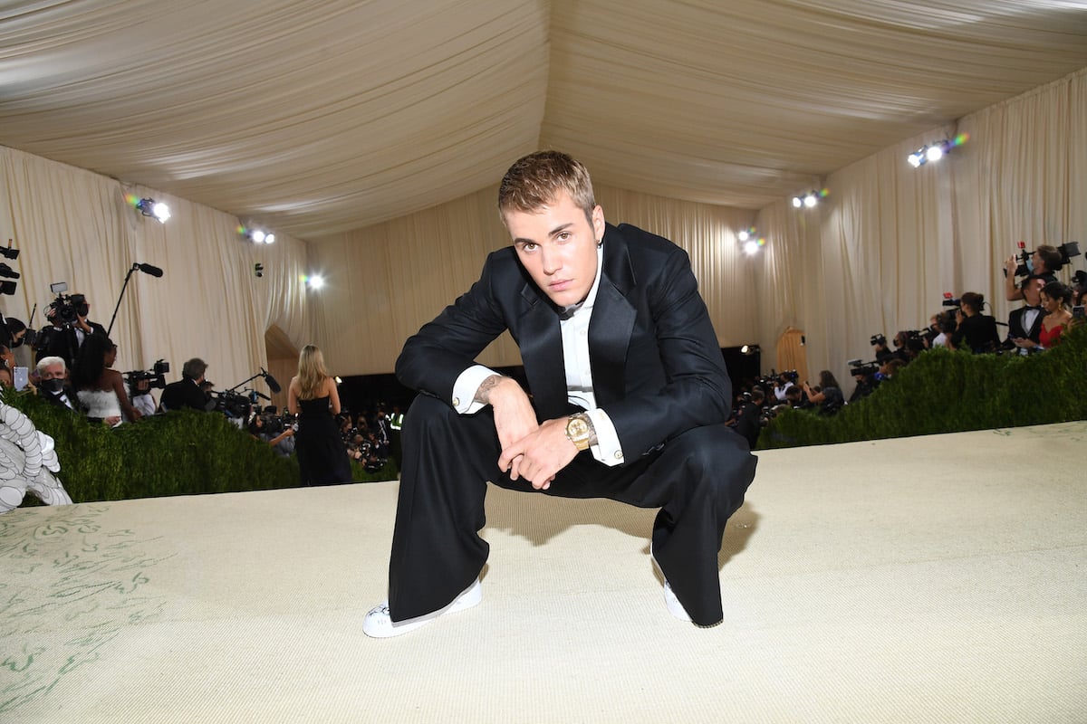 Justin Bieber squats in a black suit at the 2021 Met Gala.