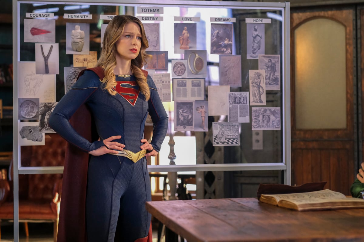 'Supergirl' Season 6 Episode 14 actor Melissa Benoist, as her character Kara Danvers, dresses in her Supergirl costume and stands in front of an investigation board with her hands on her hips.