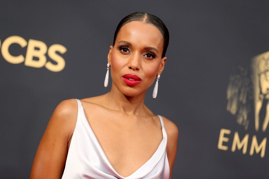 Kerry Washington dressed in a white dress against a black background with gold writing on it.