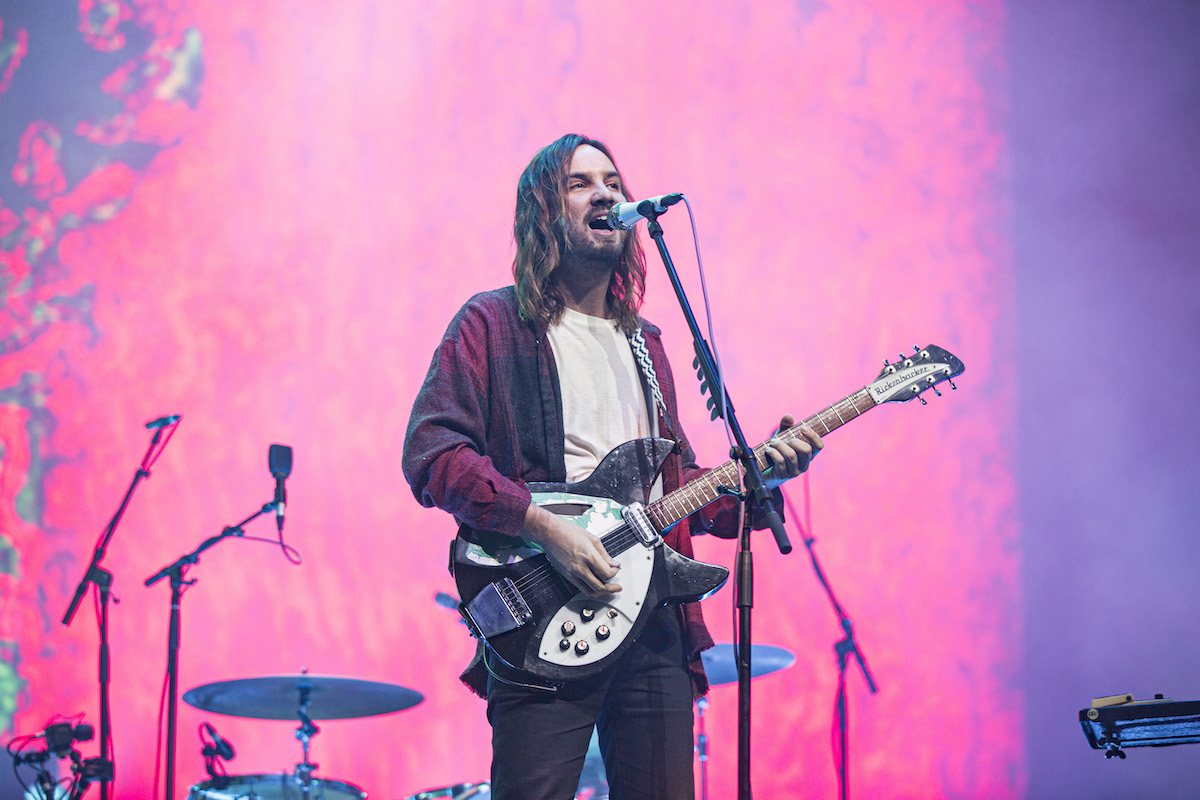 Kevin Parker from the group Tame Impala performs on stage with a guitar.