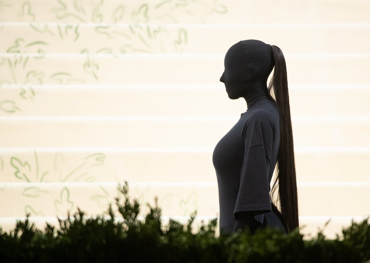 Kim Kardashian West in a full body t-shirt, in profile, in front of a set of white carpeted stairs