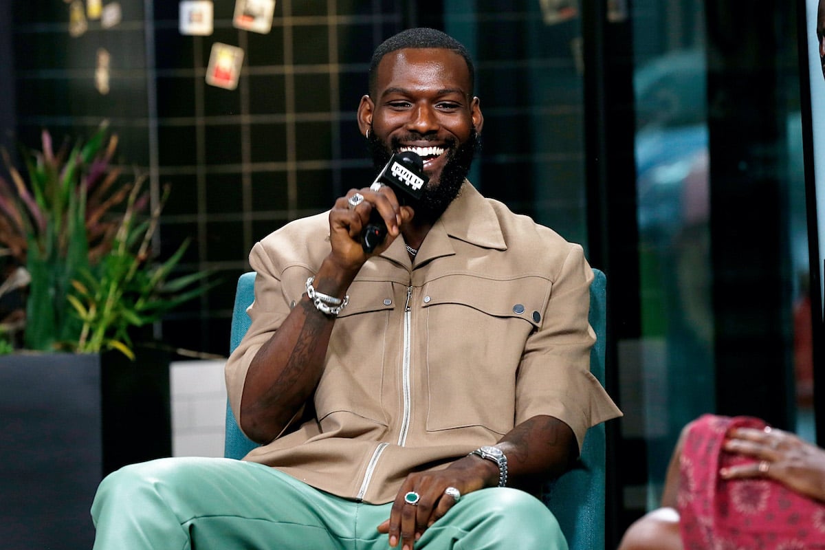Kofi Siriboe wears a light-colored outfit as he speaks at a TV event