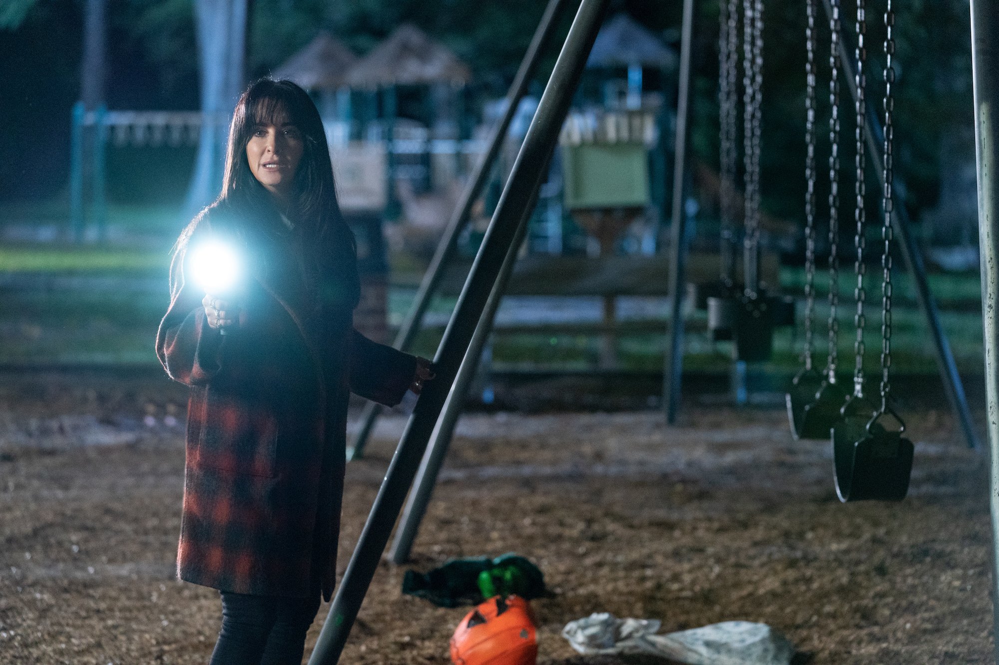 Kyle Richards holds a flashlight at a swingset in Halloween Kills