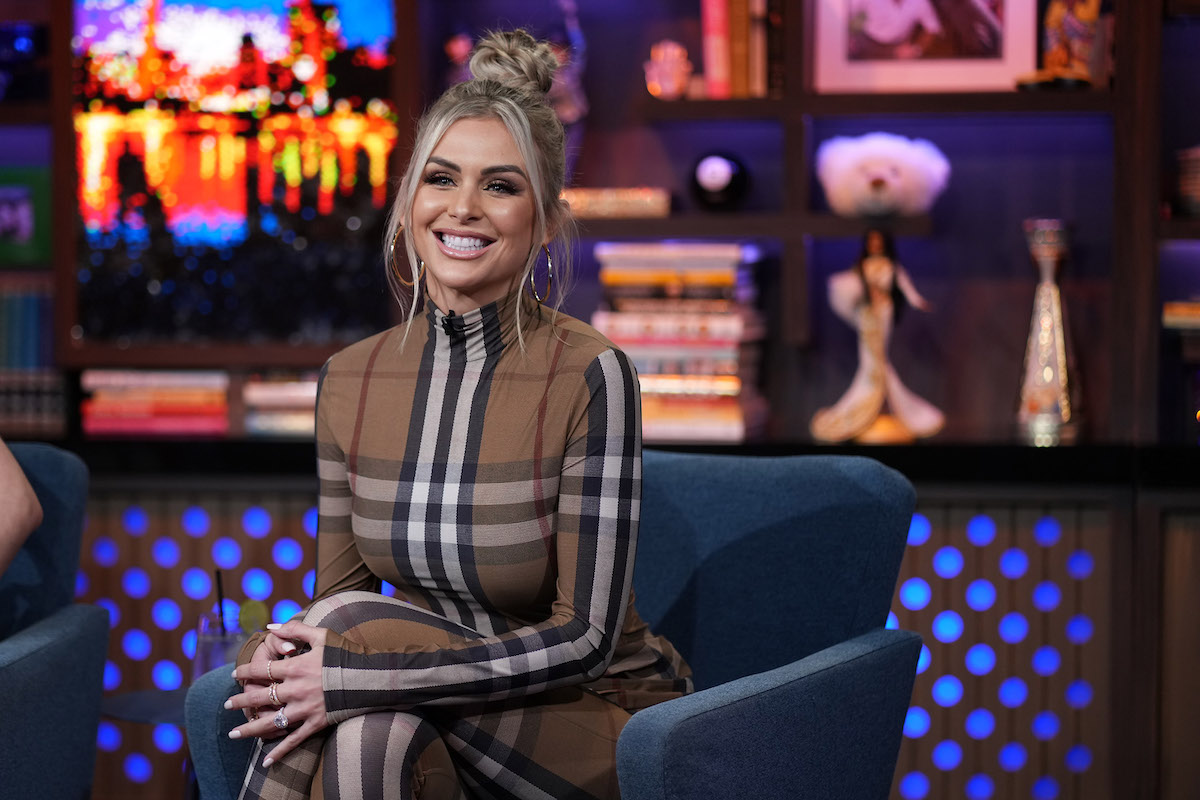 Lala Kent sits on a couch and smiles.