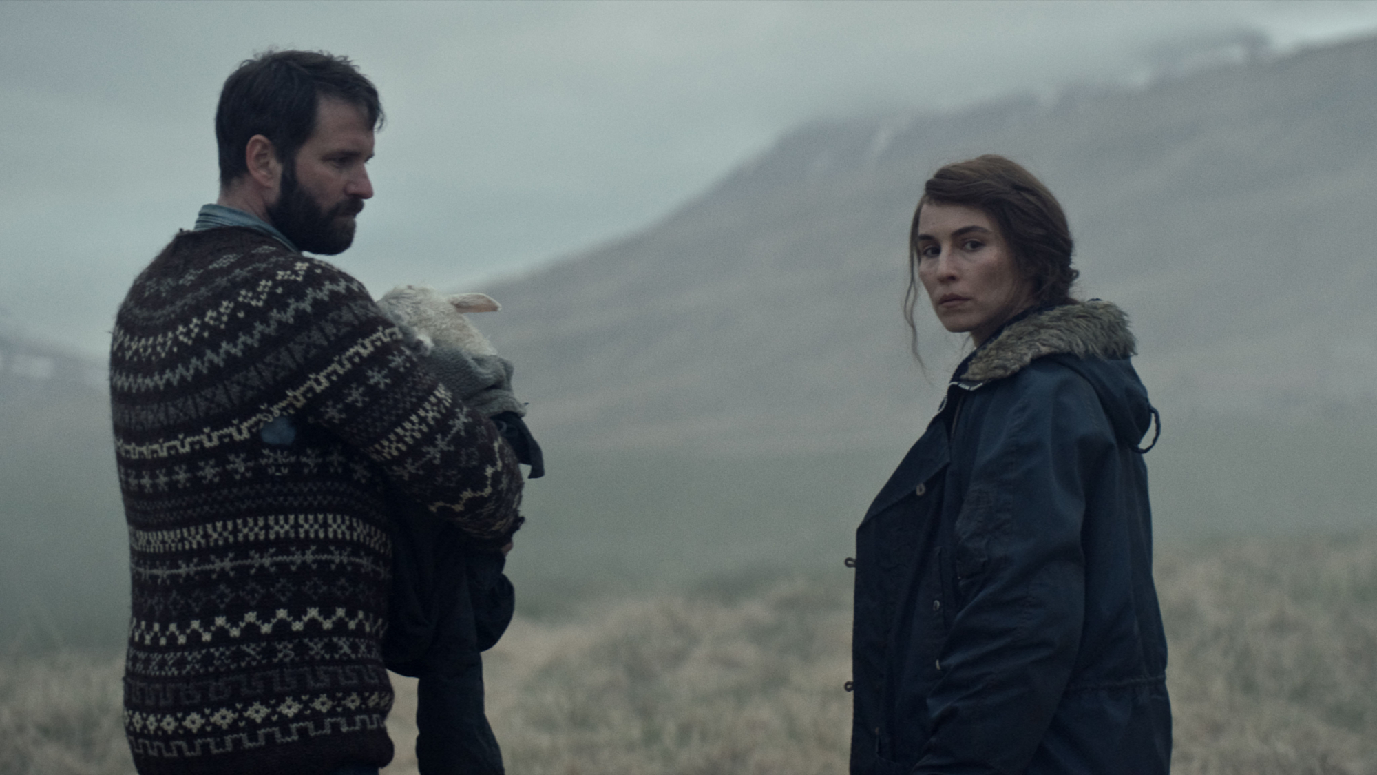 'Lamb' actors Hilmir Snær Guðnason as Ingvar and Noomi Rapace as Maria standing outside holding Ada