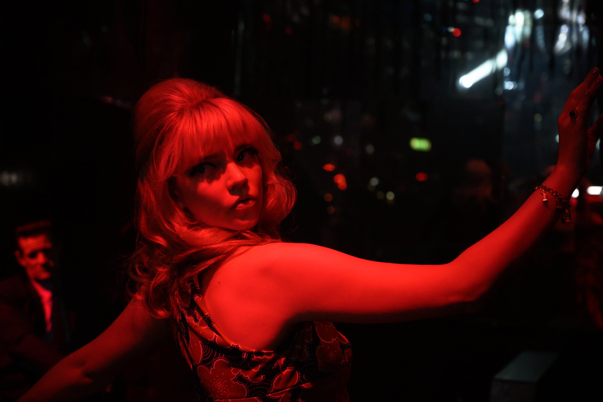 'Last Night in Soho' actor Anya Taylor-Joy looking back lit with neon red