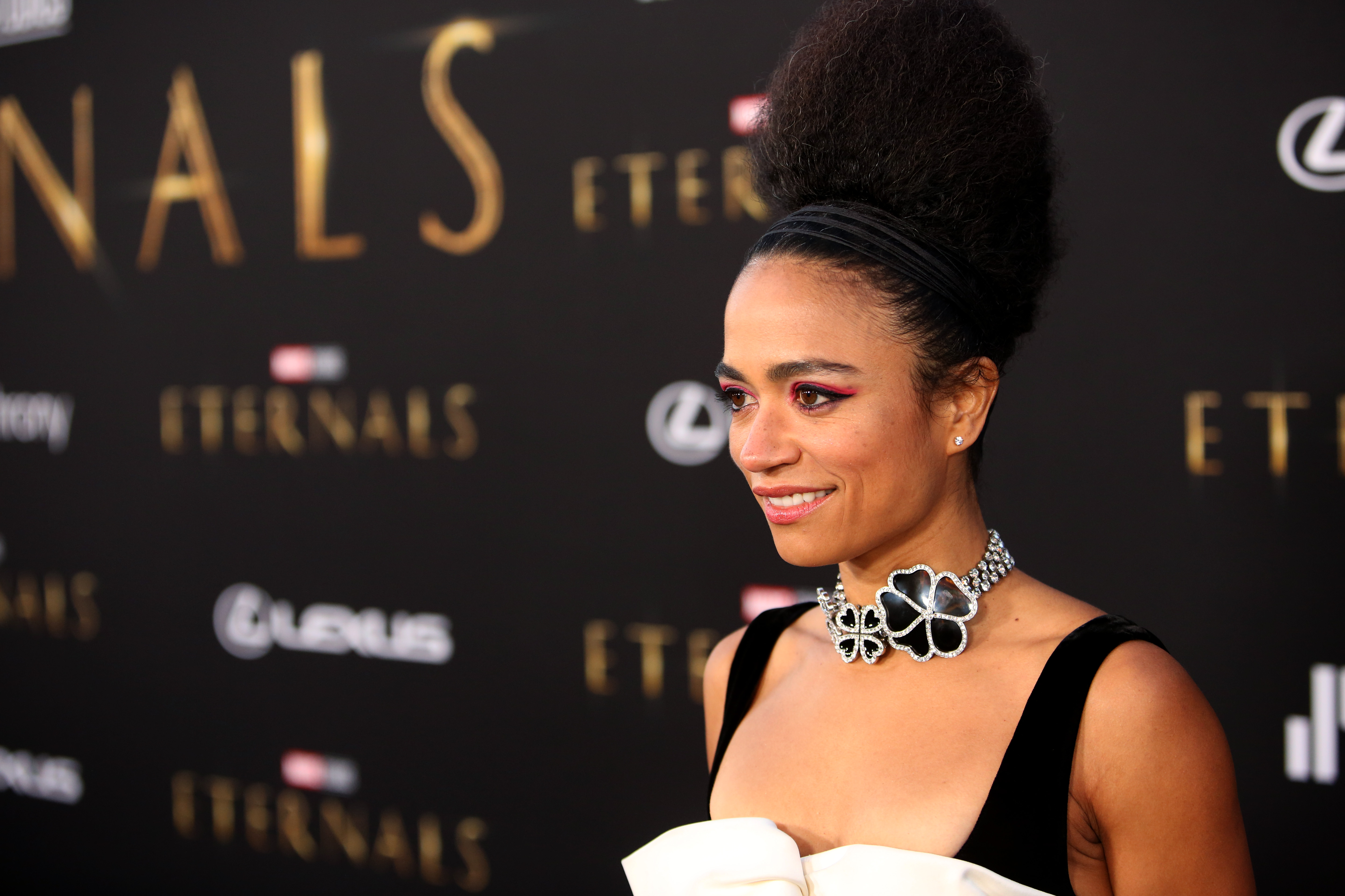 Marvel's 'Eternals' star Lauren Ridloff wears a black romper with a white bow and a diamond necklace with black flowers.