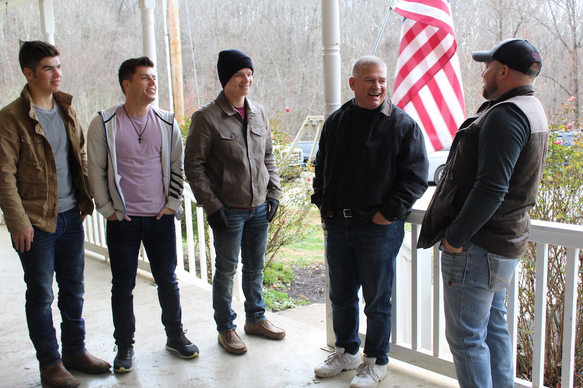 Lawson Bates, in pink shirt, stands with other members of his family on a front porch in an episode of 'Bringing Up Bates'