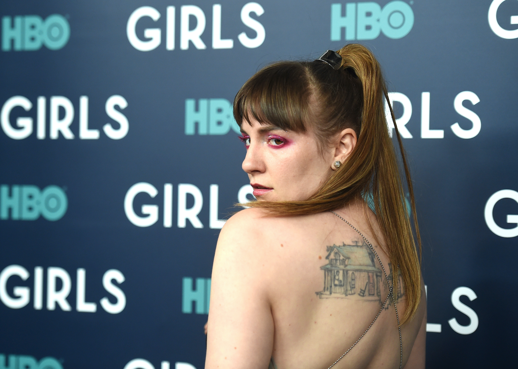 Lena Dunham poses looking over her shoulder at an event for HBO 'Girls'