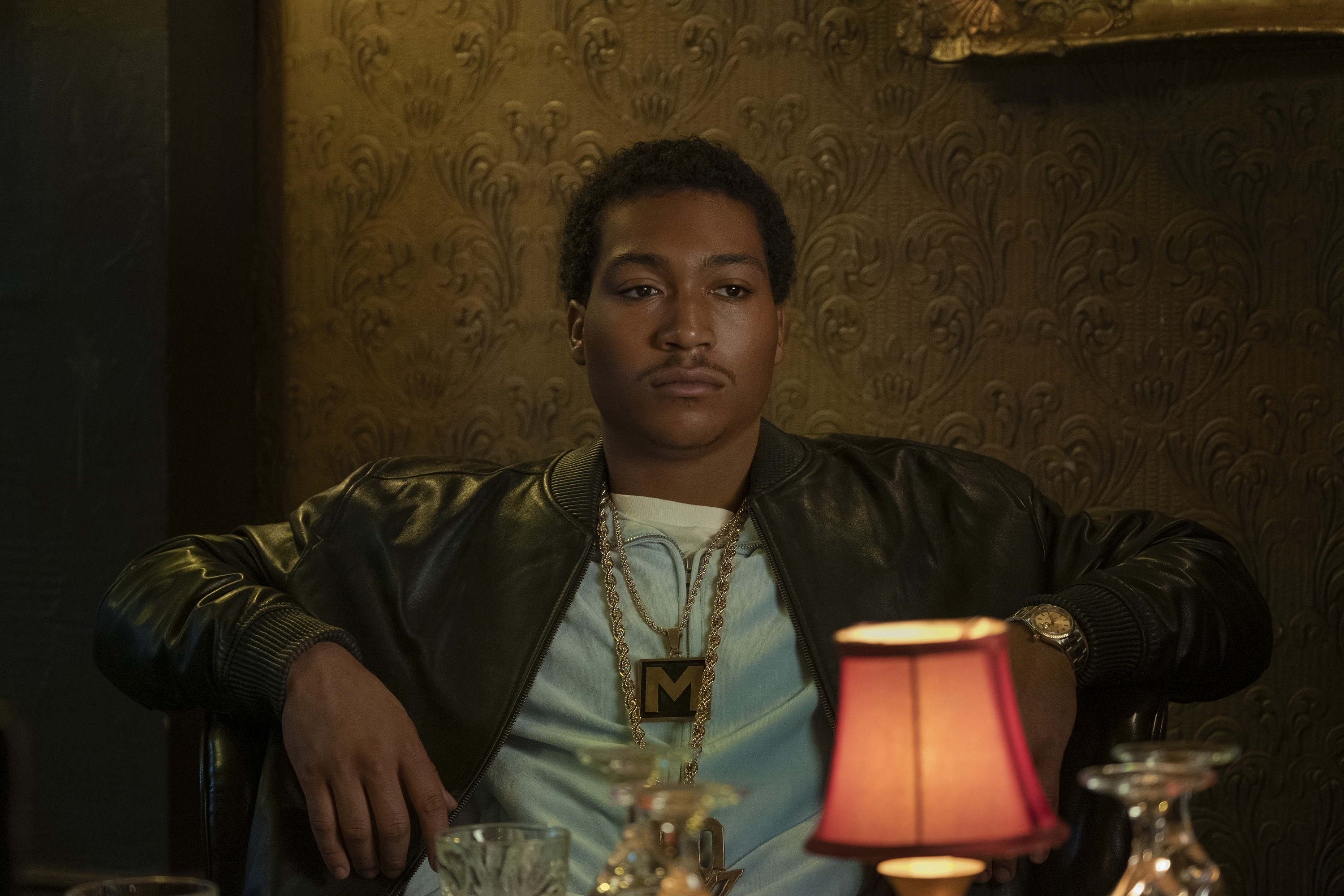 Demetrius “Lil Meech” Flenory Jr. as Demetrius “Big Meech” Flenory sitting at a table looking stoic while wearing gold chains in 'BMF'