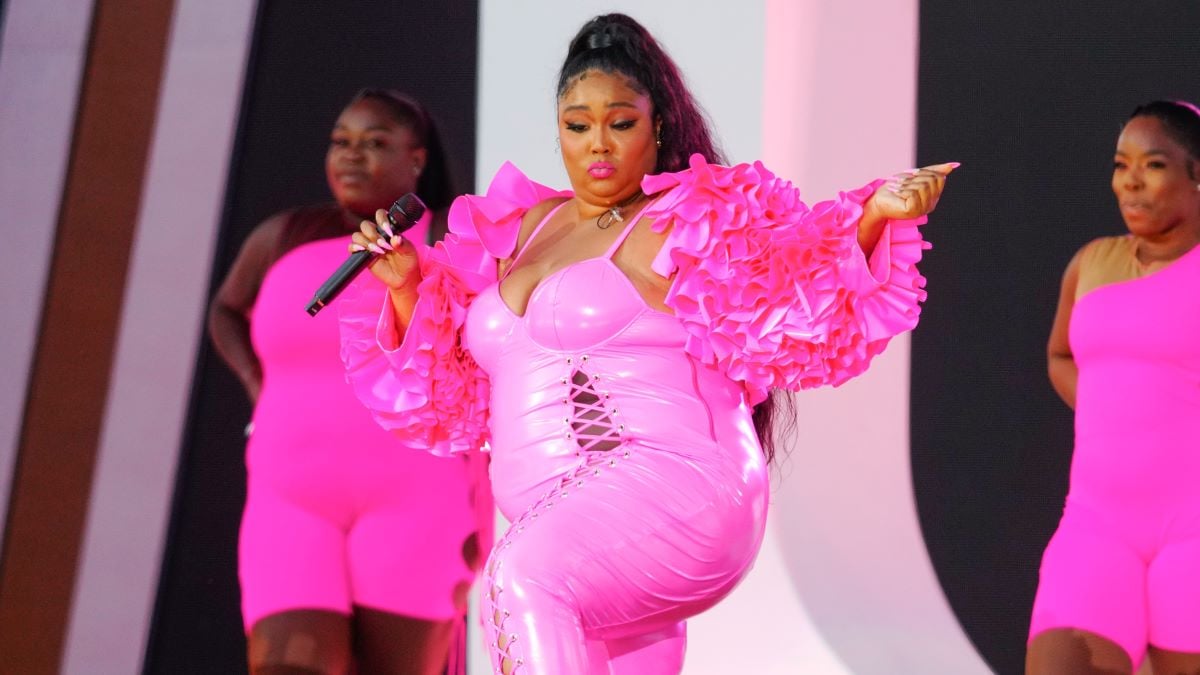 Lizzo dancing in pink catsuit, two backup dancers behind her
