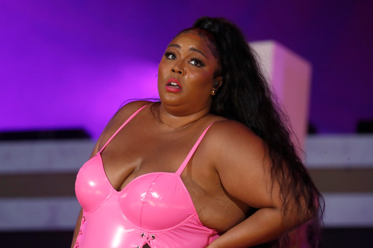 Lizzo performs on stage in a bright pink outfit.