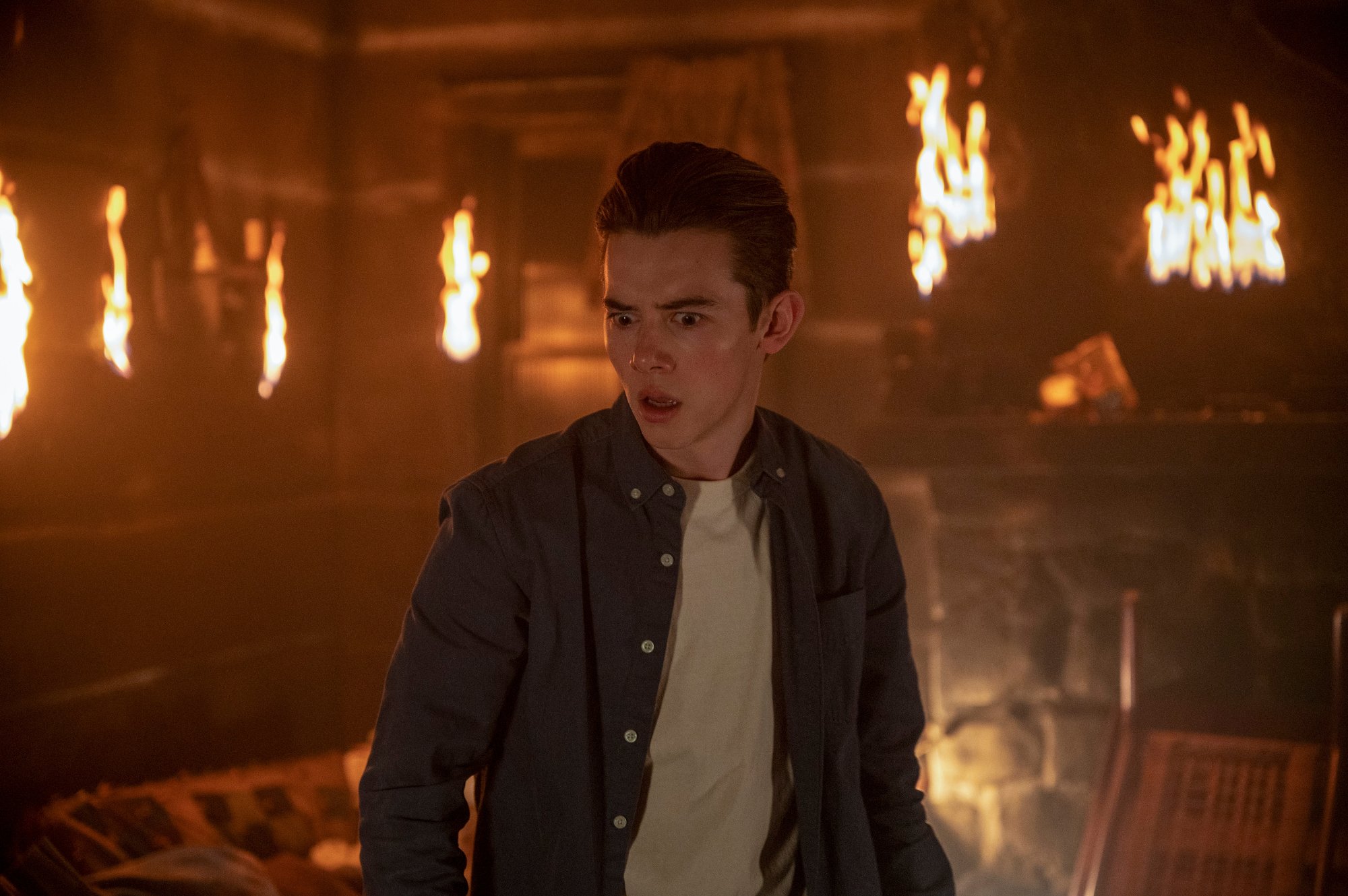 Griffin Gluck as Gabe in 'Locke & Key' Season 2. There's fire around him and he looks angry and surprised.