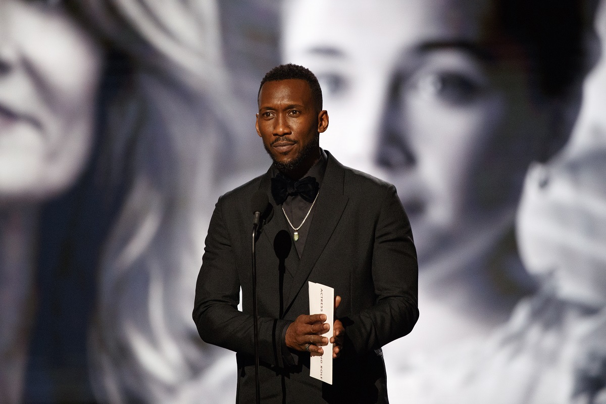 Mahershala Ali posing in front of a microphone