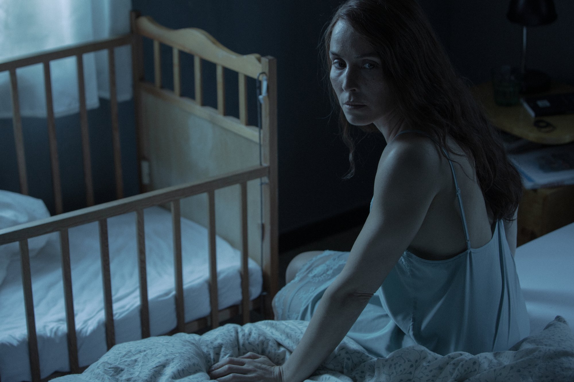 Maria turns around in the dark in A24 Lamb horror movie