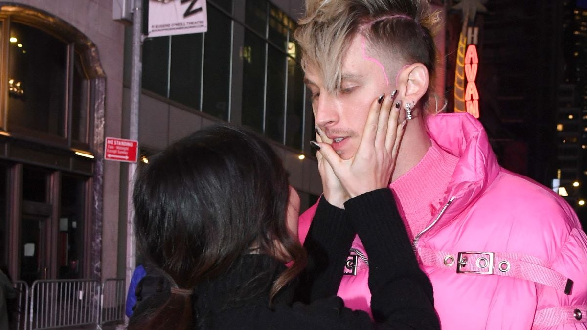 Megan Fox in black holds the face of boyfriend Machine Gun Kelly in pink 