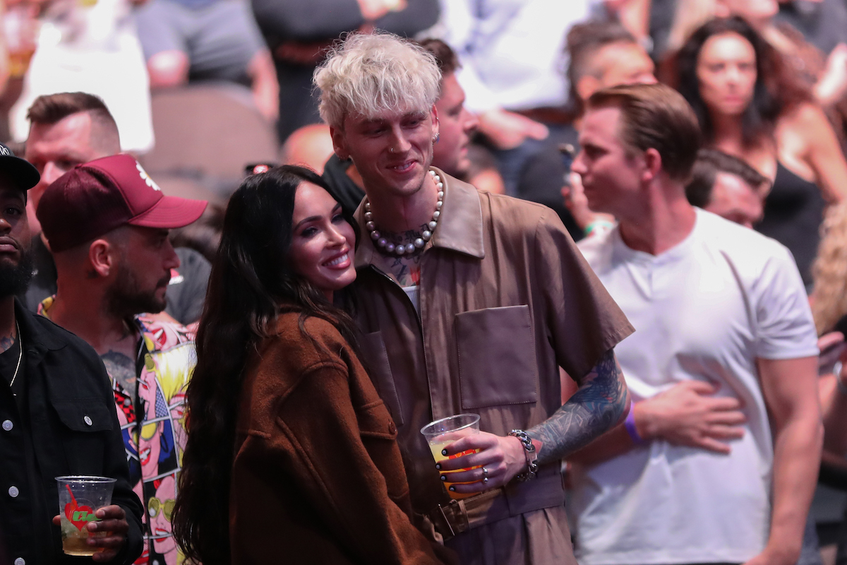 Megan Fox and Machine Gun Kelly smile and hold each other at an event.
