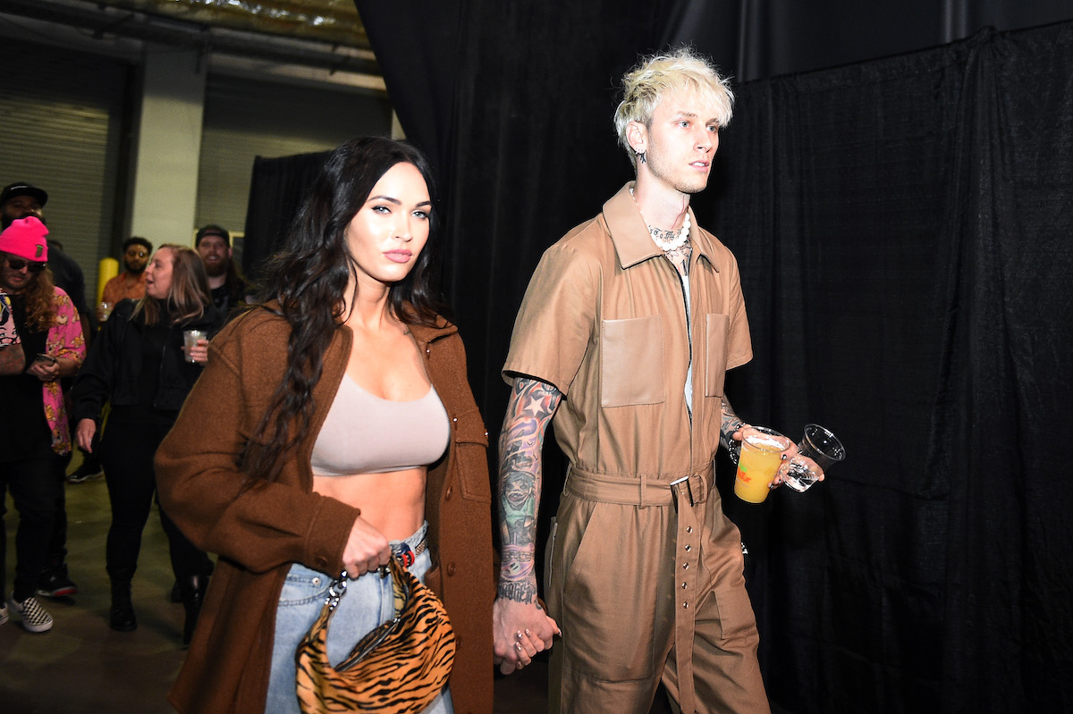 Megan Fox and Machine Gun Kelly hold hands while walking at an event.