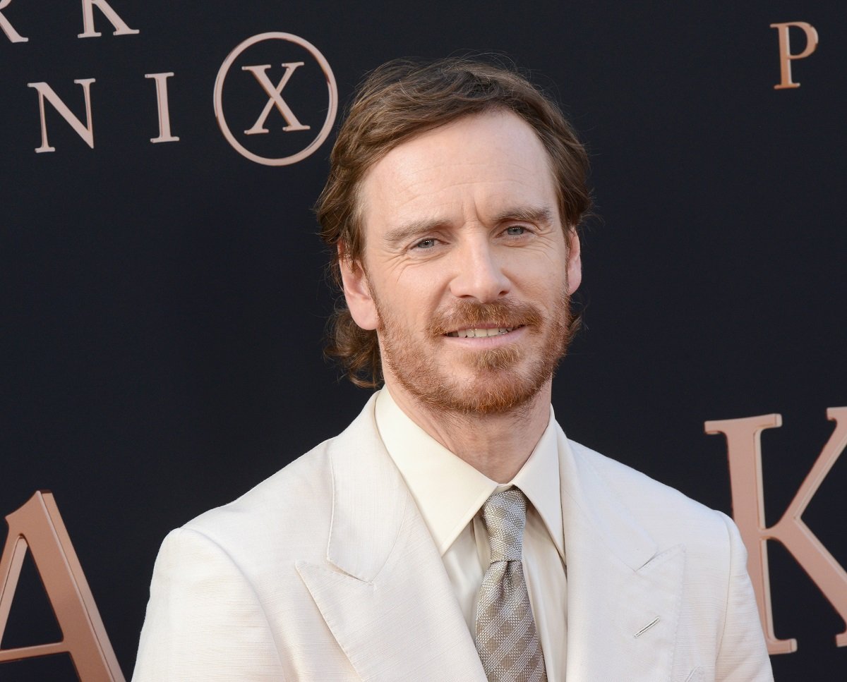 Michael Fassbender smiling wearing a white suit