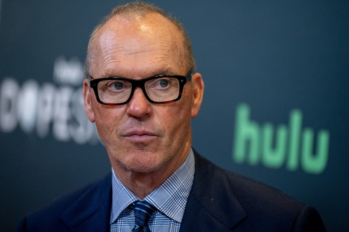 Michael Keaton staring while wearing glasses and a suit