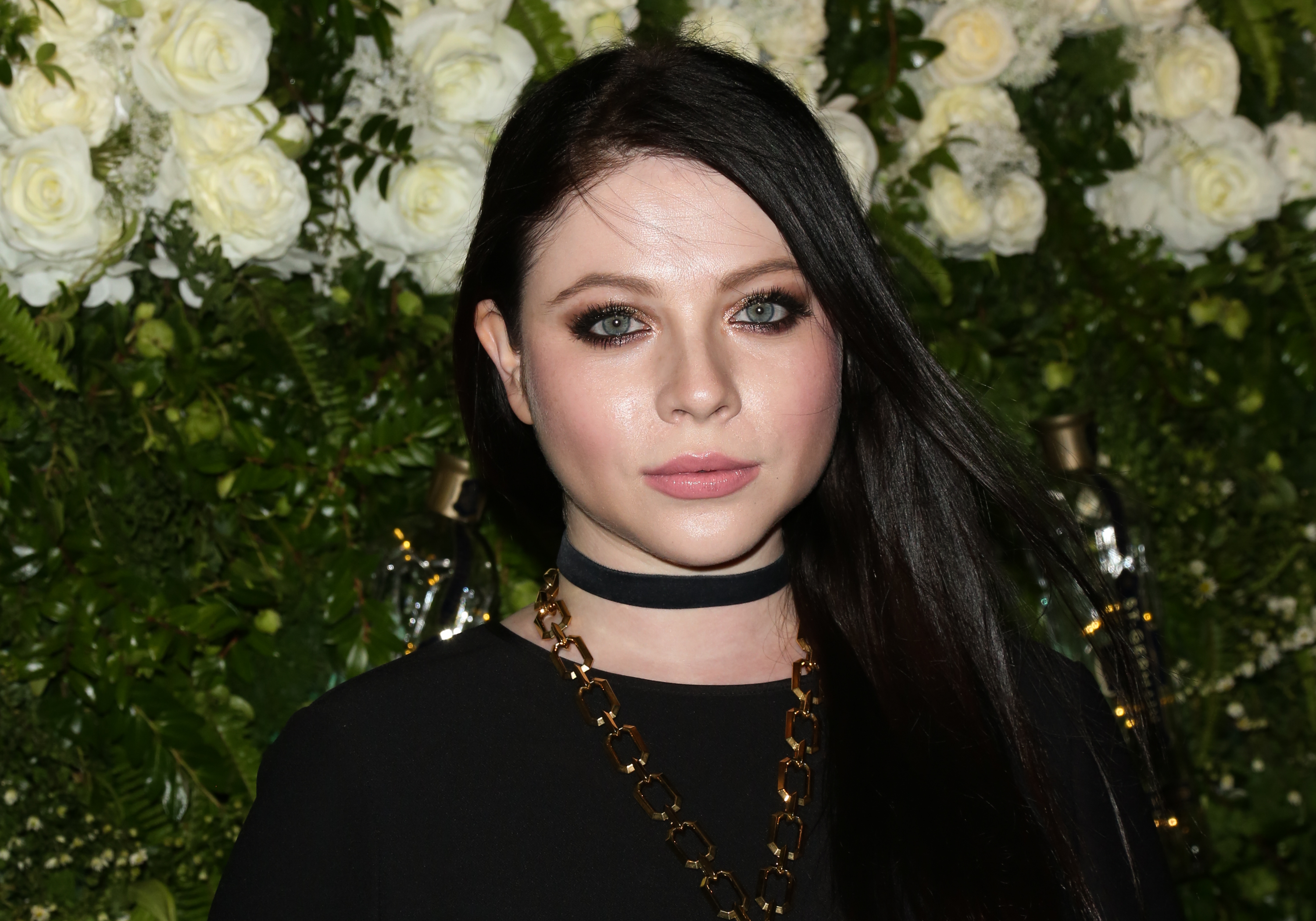 Michelle Trachtenberg wears a black dress and a large gold chain while posing for photographers at Maison St-Germain LA