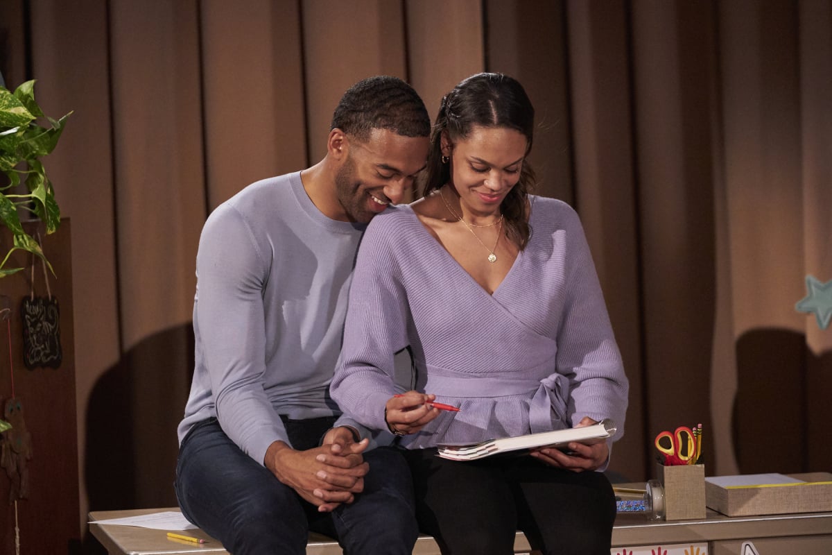 Matt James and Michelle Young sit holding hands and smiling while looking at a planner on 'The Bachelor.' Young will be the bachelorette on season 18. 